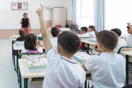 Millî Eğitim Bakanlığı logosu ve özel okul binası önünde karekod taraması yapan bir veli